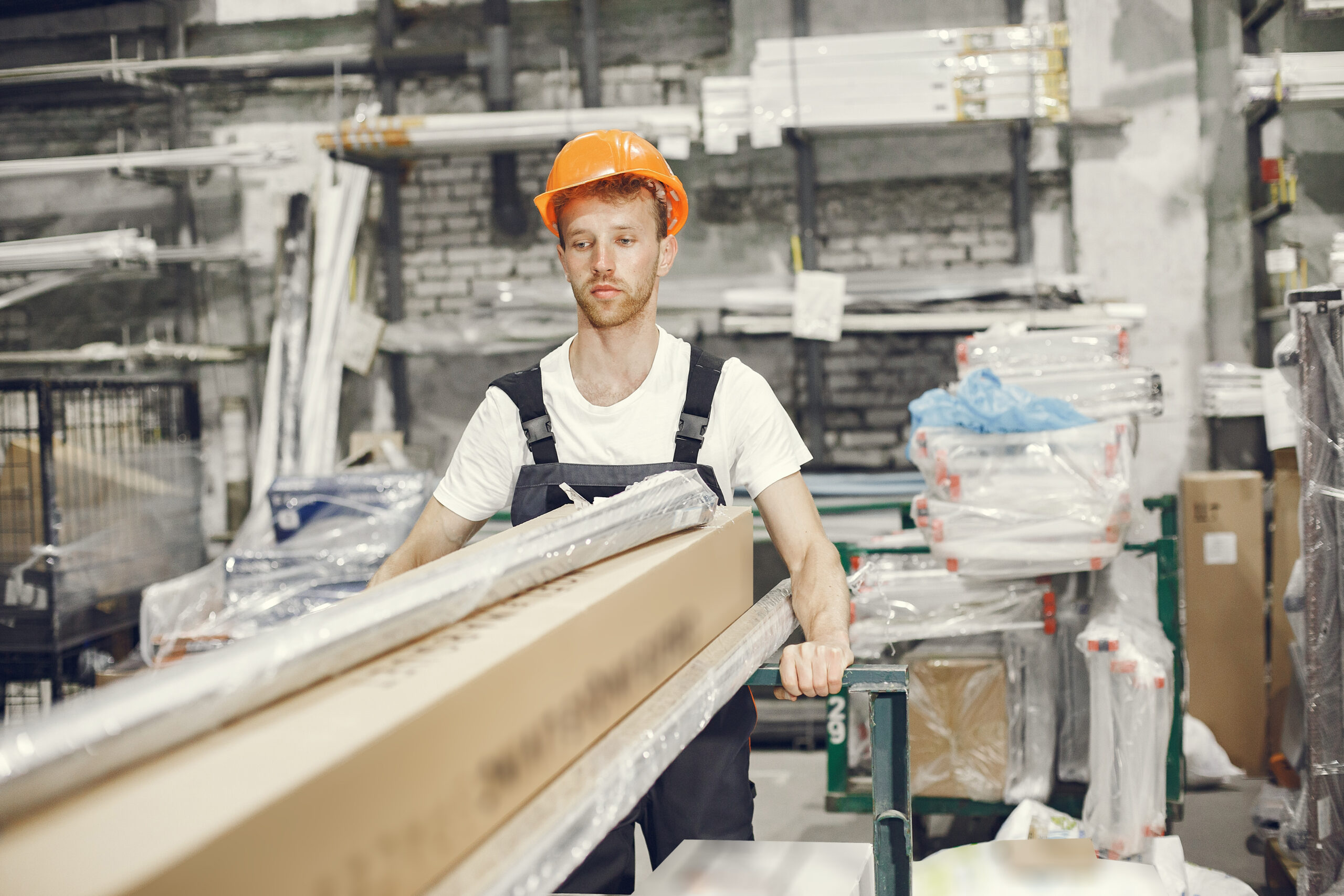 Industrial worker indoors in factory. Young technician with orange hard hat.